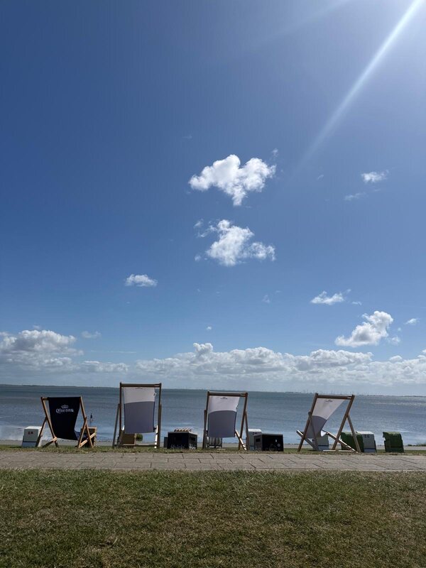Reihe von Liegestühlen auf der Deichwiese unter blauem Himmel